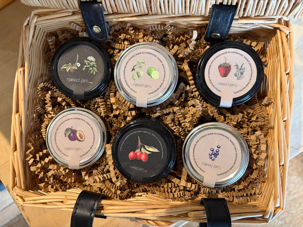 Set of six small jars with decorative lids in a wicker basket